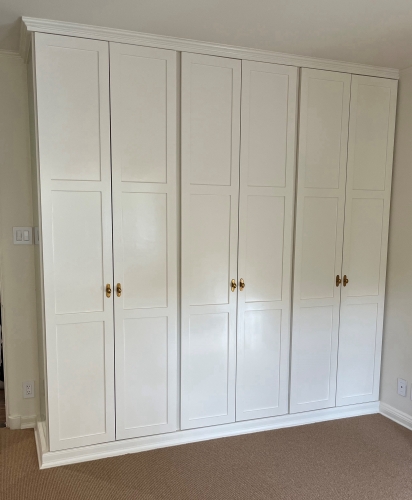 A solid wood wardrobe at 24 inches deep where doors close cleanly over all hanging garments